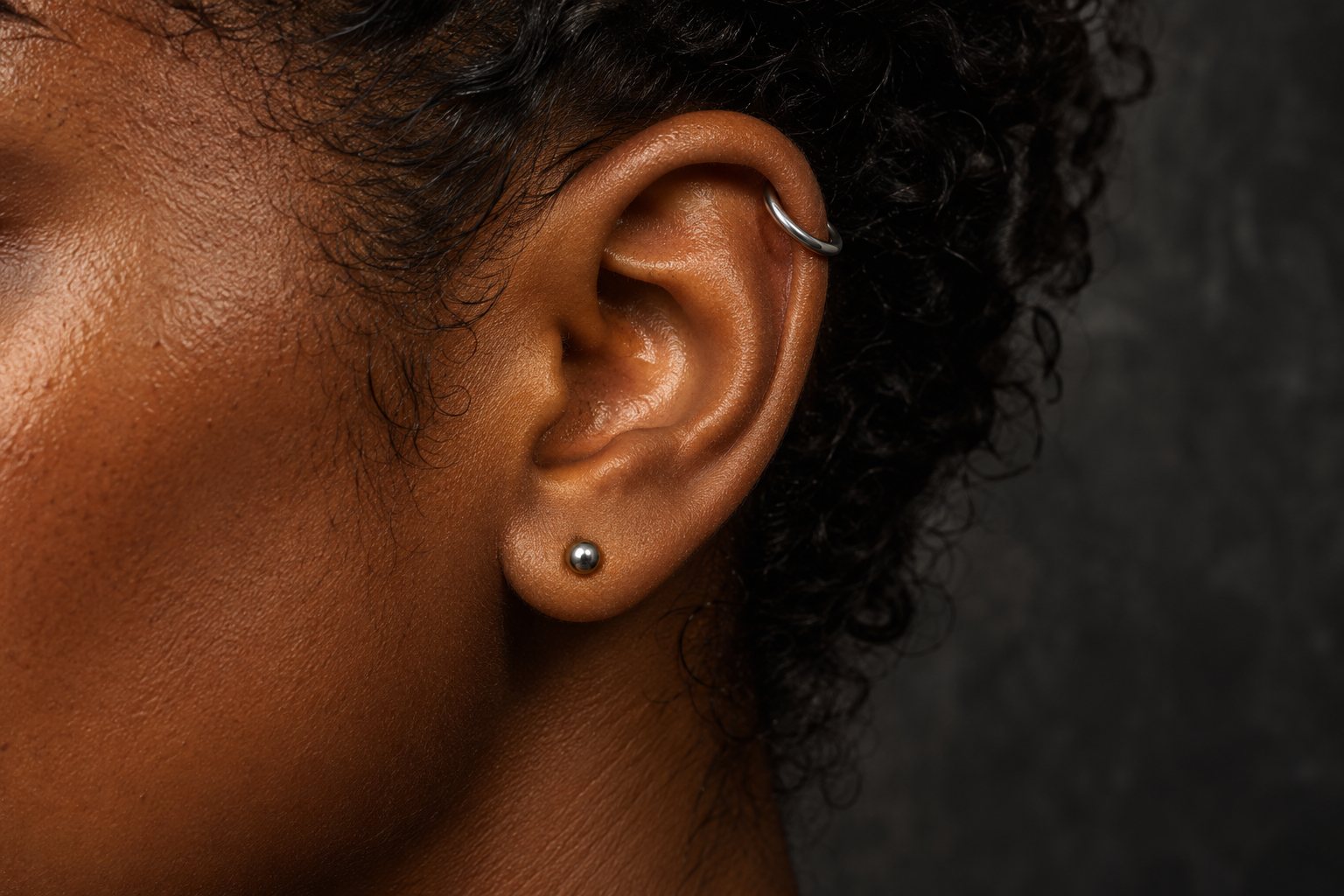 Illustrative ear with titanium piercing jewelry